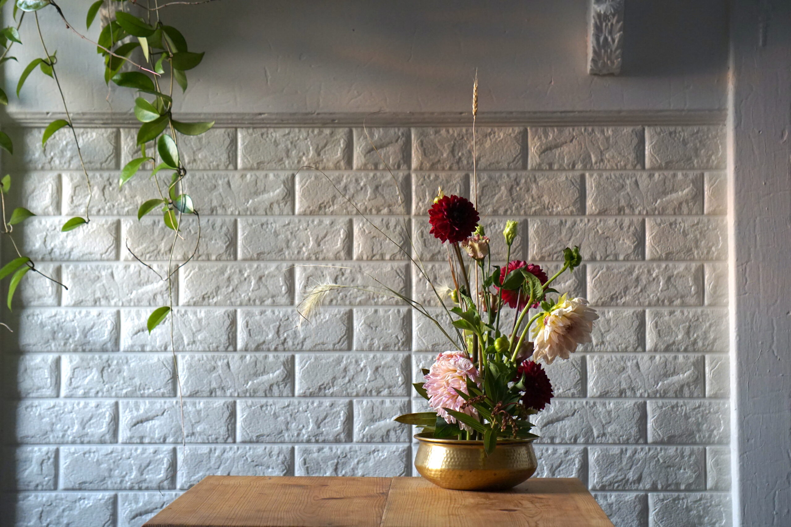 purple and pink dahlia arranged in a brass bowl with white background